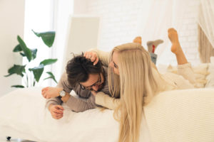 Photo of a couple laughing while laying on a bed. Discover how Online Couples Therapy in California can help you find the connection you've lost in your relationship. Click here to learn more!