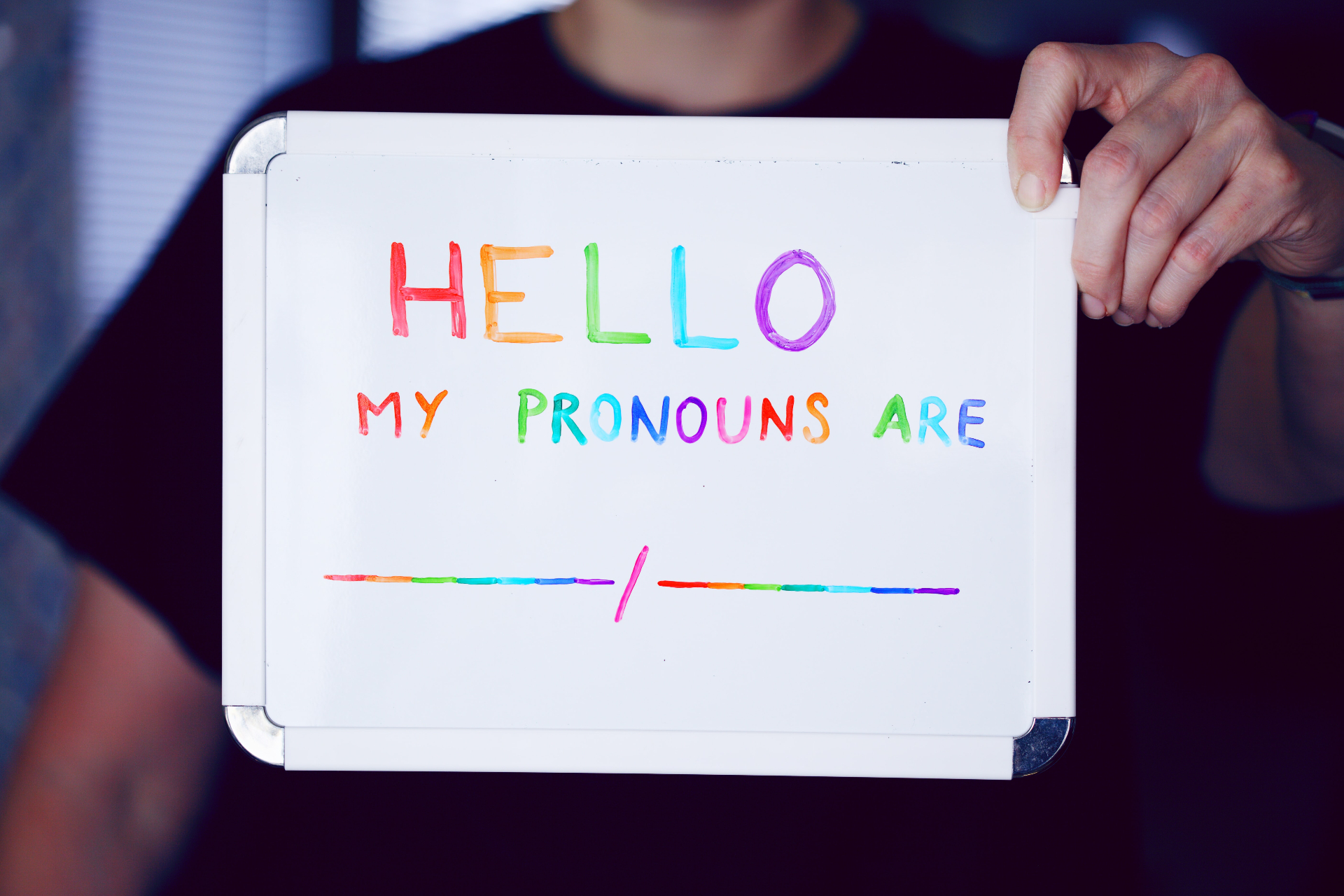 Photo of a teen holding a whiteboard that reads "Hello my pronouns are". This photo represents the support teen therapy in Marin County, CA can provide teens who feel lost with their gender identity. 