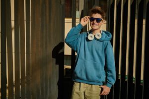 Photo of a teen boy standing outside wearing sunglasses and smiling. Is your teen struggling with their ADHD? Learn how therapy for teens with ADHD in Marin County, CA can help your teen learn the coping skills to reduce and manage their symptoms.