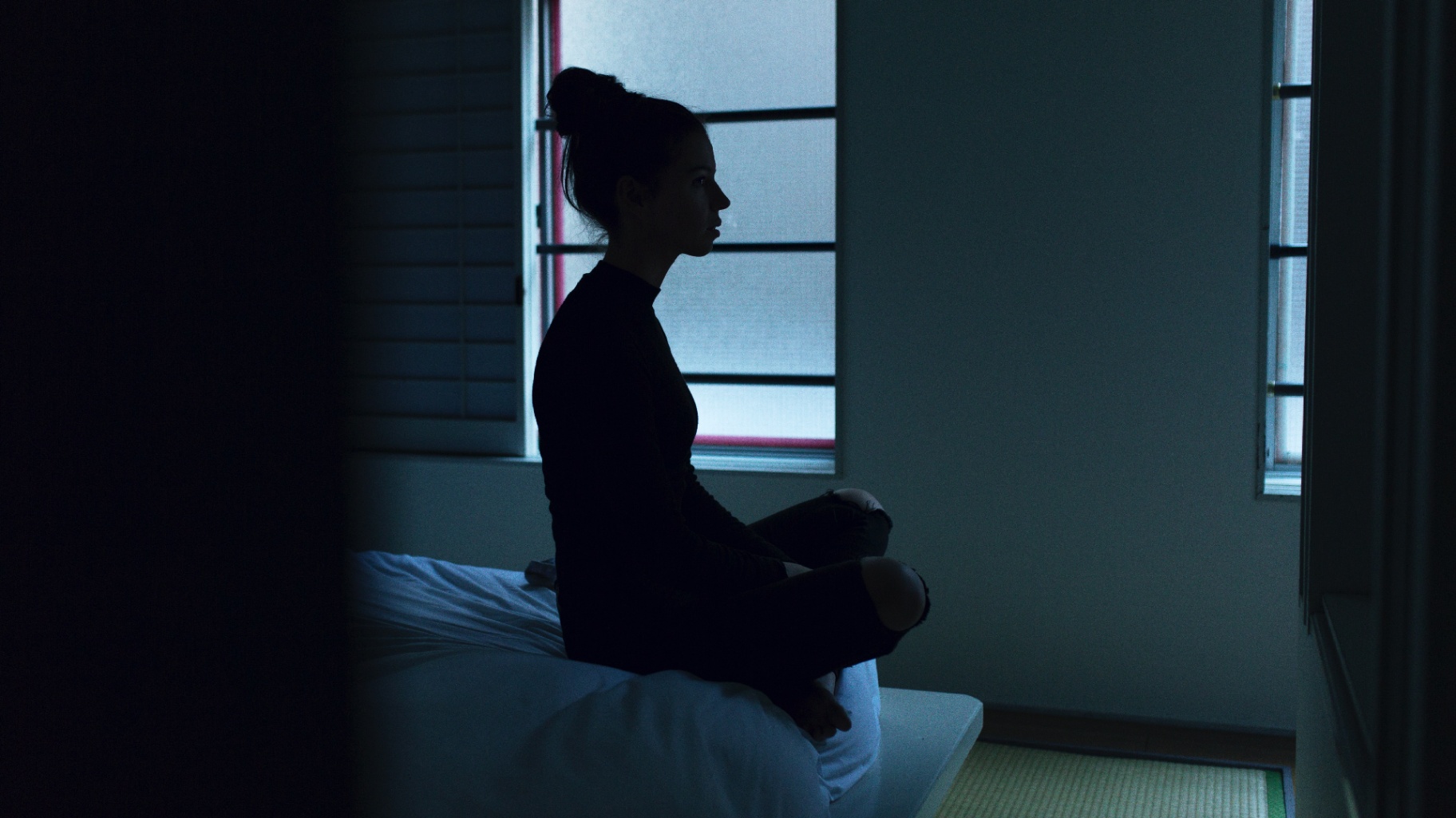 Photo of a woman sitting in a dark room. This photo represents how one may feel when dealing with postpartum symptoms. With postpartum therapy in San Francisco, CA you can begin to cope with your postpartum symptoms.