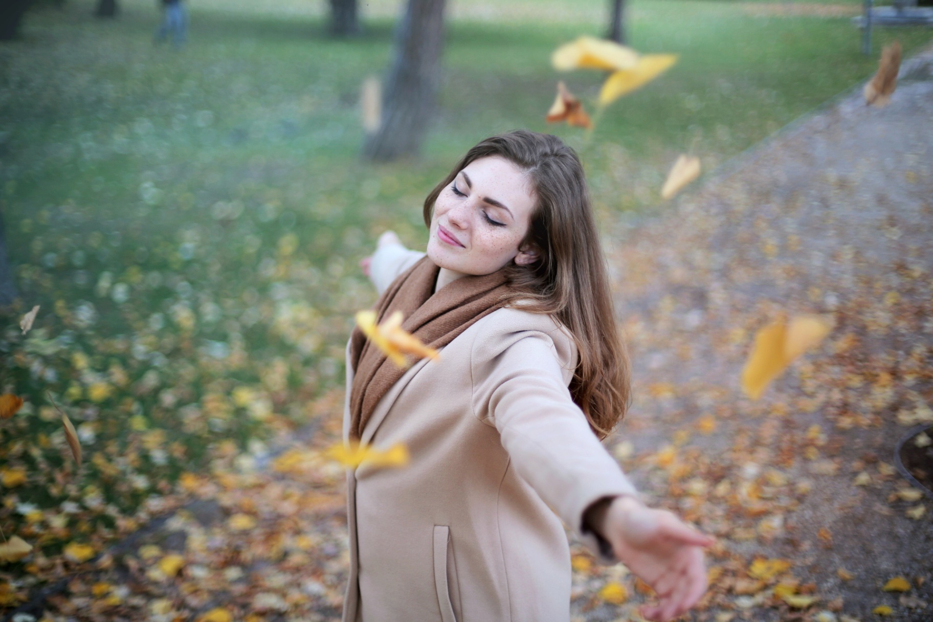 Photo of a woman standing outside twirling in falling leaves. This photo represents how anxiety therapy in San Francisco, CA can help you start to cope with you anxiety symptoms to live a stress free life.