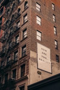 Photo of a brick building with a sign on the side that reads how are you really? Are you struggling to manage your anxiety symptoms? With anxiety therapy in the Bay Area, you can begin to manage your symptoms with an anxiety therapist. 