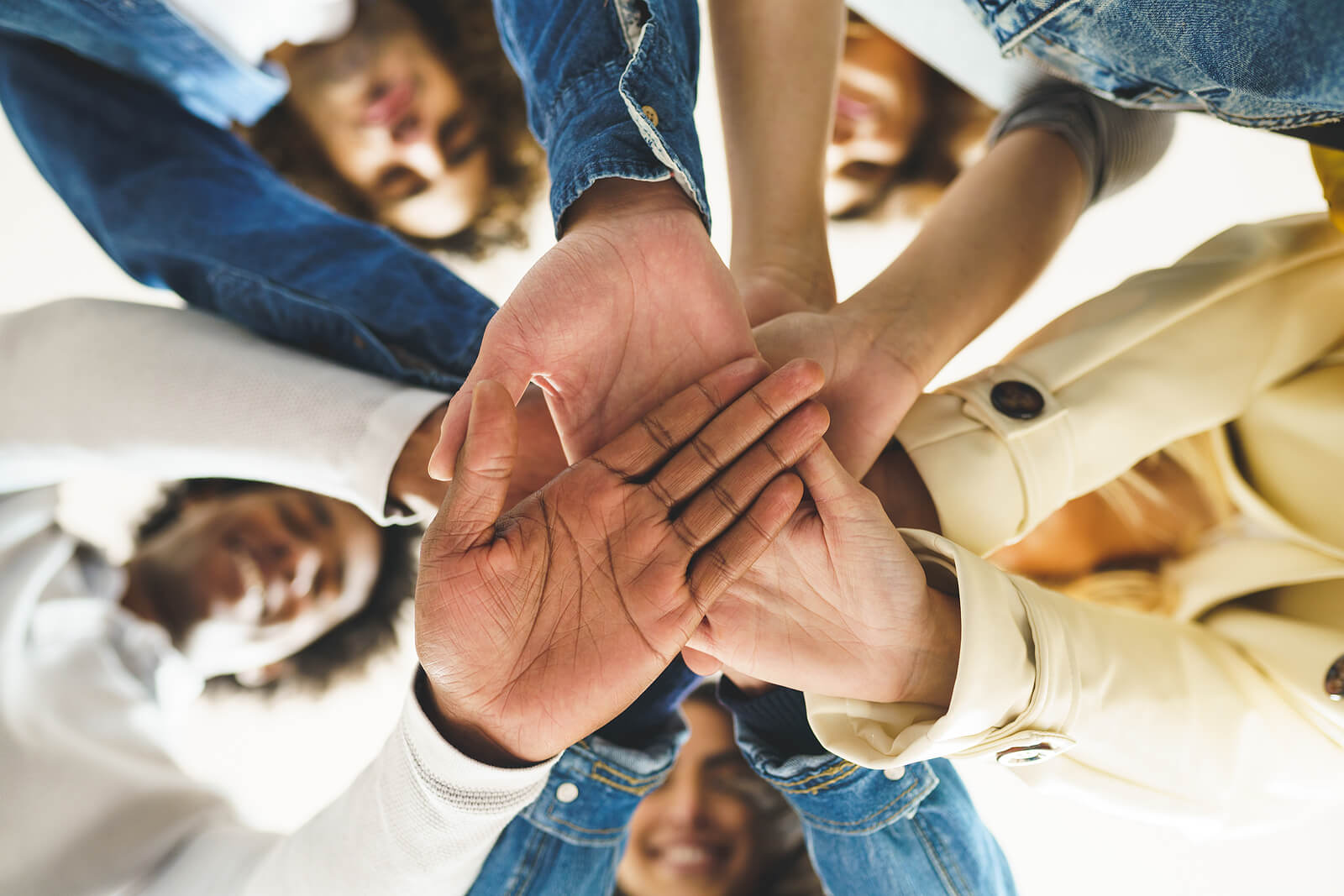 Photo of a group of teens smiling and putting their hands on top of one another's in the middle of a circle. If you teen is struggling to overcome their challenges, discover how group therapy for teens in Marin County, CA can help them feel supported.